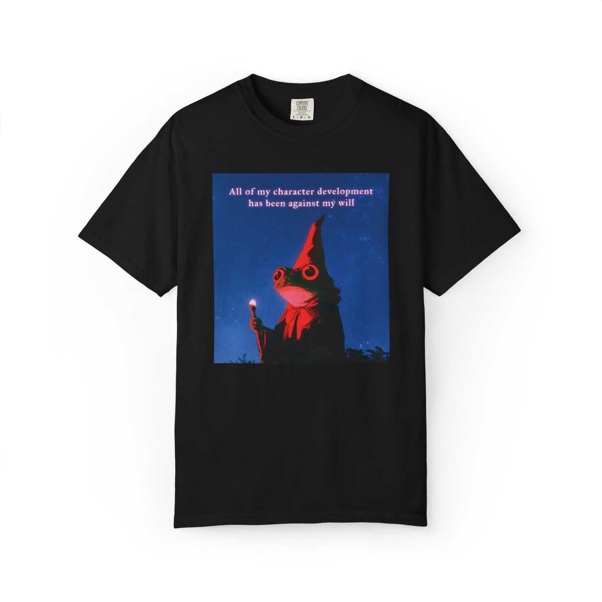 A black short-sleeve crewneck t-shirt featuring a square graphic print on the front. The graphic shows a red-eyed frog wearing a wizard hat against a dark blue background with the text 'All of my character development has been against my will'.