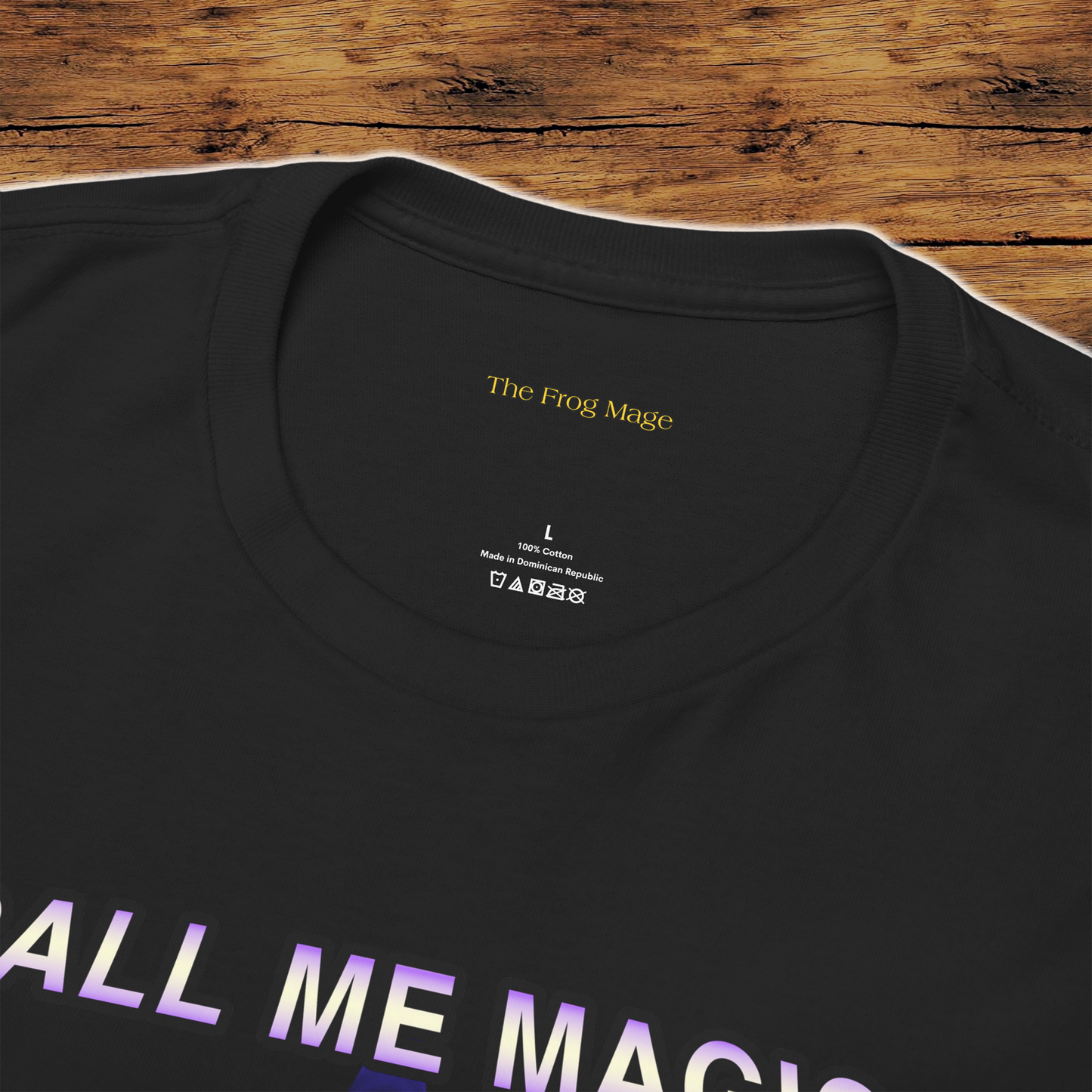 Black t-shirt with 'The Frog Mage' branding in the neck and text on a wooden surface